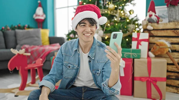 若いですヒスパニック男使用スマートフォンお祝いクリスマスに自宅 — ストック写真