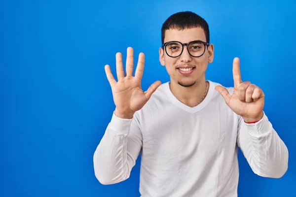 年轻的阿拉伯男子身穿随意的白色衬衫 戴着眼镜 用第七指指尖 面带微笑 自信而快乐 — 图库照片