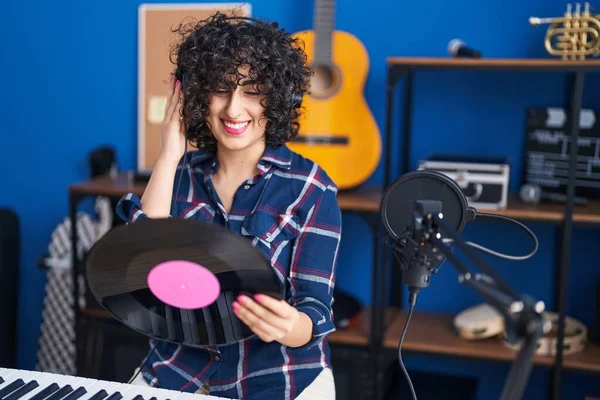 Young middle east woman musician listening music holding vinyl disc at music studio