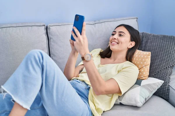 Jovem Hispânica Usando Smartphone Deitado Sofá Casa — Fotografia de Stock