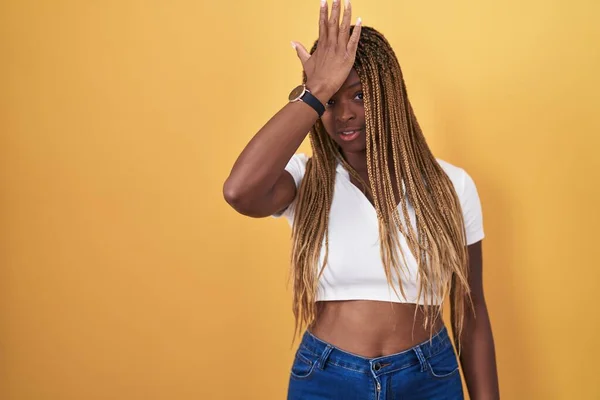 Африканская Американка Плетеными Волосами Стоящая Жёлтом Фоне Удивленная Рукой Голове — стоковое фото