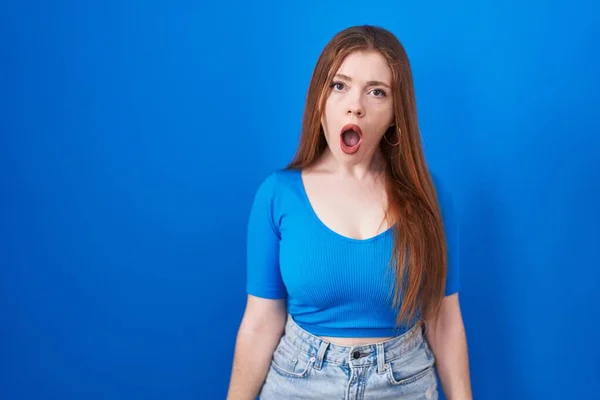 Roodharige Vrouw Staande Blauwe Achtergrond Shock Gezicht Zoek Sceptisch Sarcastisch — Stockfoto