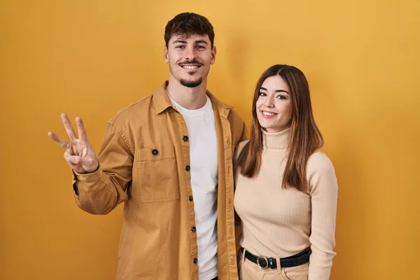 Jong Hispanic Paar Staande Gele Achtergrond Tonen Wijzen Met Vingers — Stockfoto