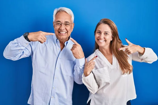 Middelbare Leeftijd Hispanic Paar Staan Blauwe Achtergrond Lachend Vrolijke Tonen — Stockfoto