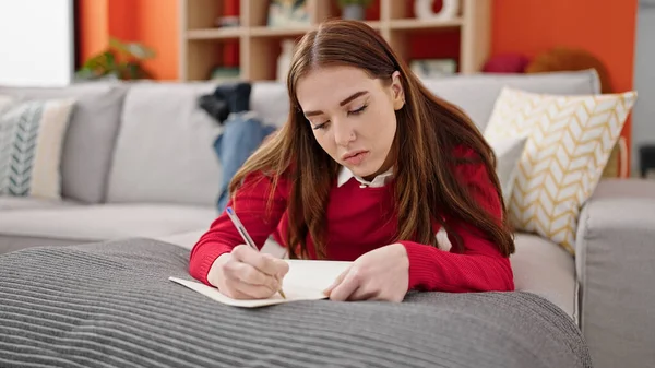 Young Hispanic Woman Writing Notebook Lying Sofa Home — Stockfoto