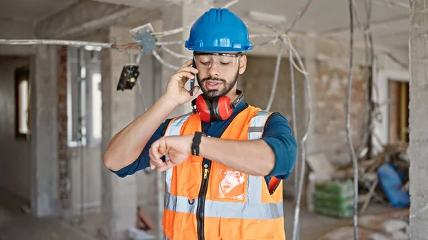 Jovem Hispânico Homem Construtor Falando Smartphone Olhando Para Relógio Pulso — Fotografia de Stock