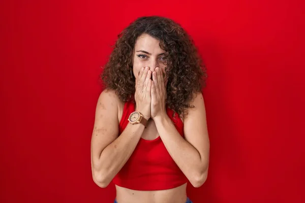 Kıvırcık Saçlı Spanyol Kadın Kırmızı Arka Planda Gülüyor Utanıyor Kıkırdıyor — Stok fotoğraf