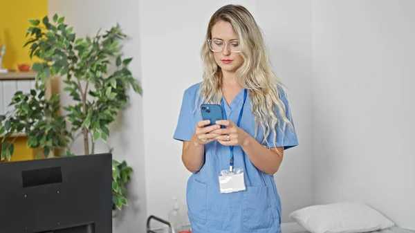 Young Blonde Woman Doctor Using Smartphone Clinic — Stock fotografie
