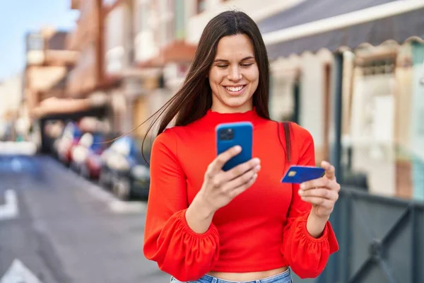 ストリートでスマートフォンやクレジットカードを使用して若い美しいヒスパニック系女性 — ストック写真