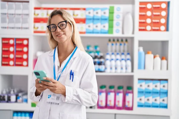 Young Blonde Woman Pharmacist Using Smartphone Working Pharmacy — 图库照片