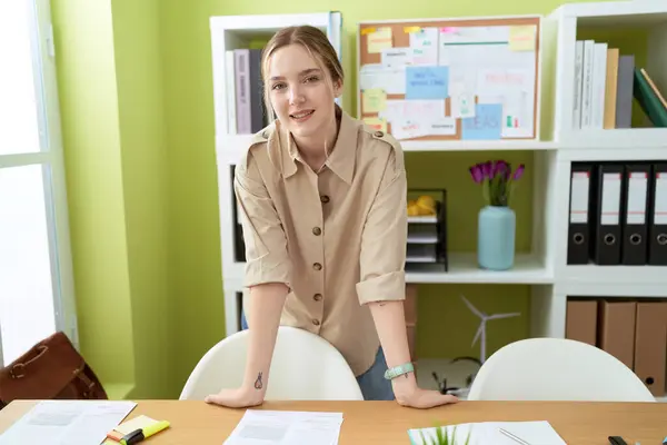 若い白人女性ビジネスワーカー笑顔自信に満ちた立ち位置にデスクでオフィス — ストック写真