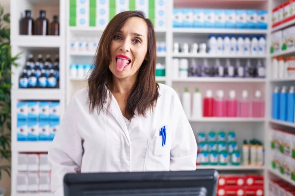 薬局で働く中年のブルネットの女性が面白い表情で幸せ舌を突き出しています 感情の概念 — ストック写真