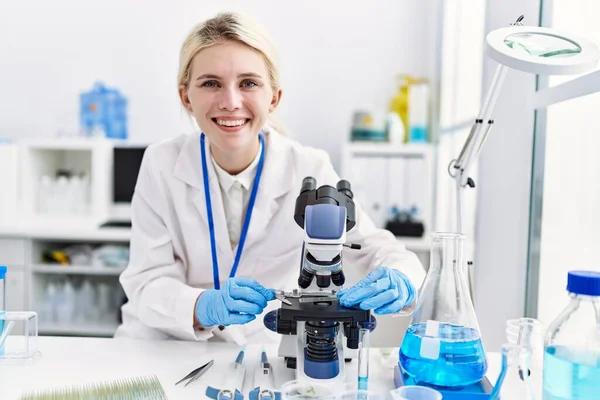 Νεαρή Ξανθιά Γυναίκα Επιστήμονας Χρησιμοποιώντας Μικροσκόπιο Χαμογελώντας Στο Εργαστήριο — Φωτογραφία Αρχείου
