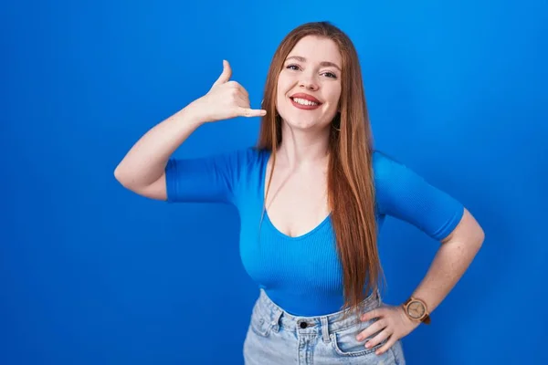 電話で話すような手や指で携帯電話のジェスチャーを行う笑顔青い背景の上に立っている赤毛の女性 コミュニケーションの概念 — ストック写真