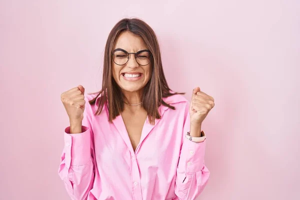 Молодая Латиноамериканка Очках Стоящая Розовом Фоне Взволнована Успехом Поднятыми Руками — стоковое фото