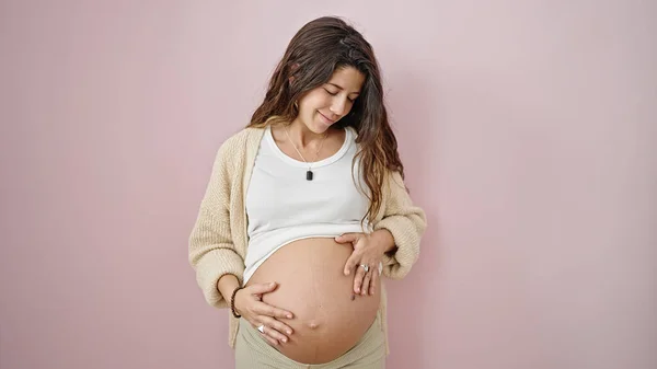 Young Pregnant Woman Smiling Confident Massaging Belly Isolated Pink Background — ストック写真