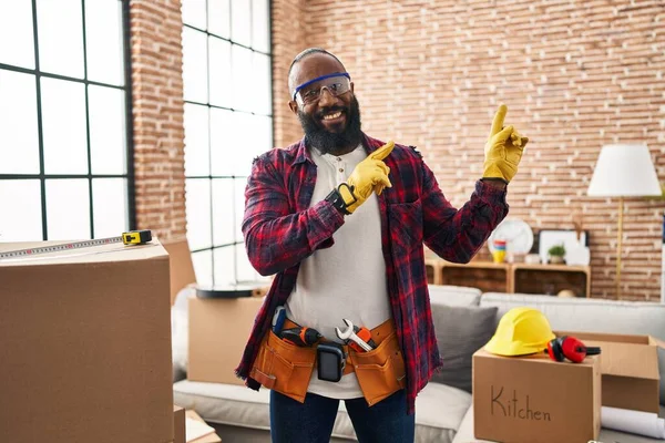 Africký Američan Pracující Renovaci Domova Úsměvem Při Pohledu Kameru Ukazuje — Stock fotografie