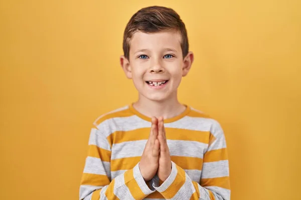 Sarı Arka Planda Dikilen Beyaz Bir Çocuk Ellerini Birleştirip Diliyor — Stok fotoğraf