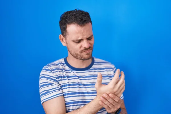 年轻的惊慌失措的男人站在蓝色的背景上 手指头疼痛 关节炎发炎 — 图库照片