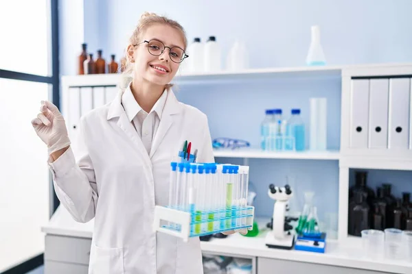 側に手と指で笑顔サンプルを保持している科学研究所で働く若い白人女性 — ストック写真