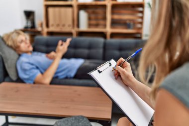 Psikoloji kliniğindeki kanepede yatan genç sarışın adam.