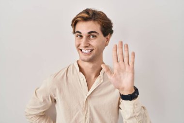 İzole edilmiş arka planda duran genç adam merhaba diyor mutlu, güler yüzlü, dostça bir hoş geldin jesti. 