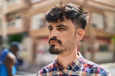 Young hispanic man looking to the side with relaxed expression at street