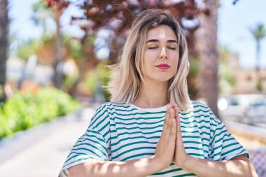 Genç bir kadın parkta yoga egzersizi yapıyor.