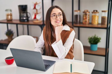 Genç, güzel, İspanyol bir kadın masada oturmuş, evde ders çalışıyor.