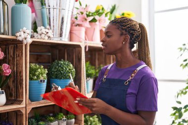 Afrikalı Amerikalı kadın çiçekçi çiçekçide belgeye yazı yazıyor.