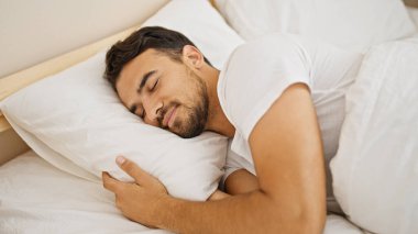 Genç İspanyol adam yatakta uzanıp yatak odasında uyuyor.