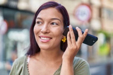 Genç ve güzel İspanyol kadın gülümsüyor. Caddedeki akıllı telefondan kendine güvenen bir sesli mesaj dinliyor.
