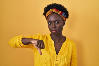 Afrika sarığı giyen Afrikalı genç bir kadın mutsuz görünüyor ve reddediliyor ve olumsuz bir hareket yapıyor. kötü ifade. 