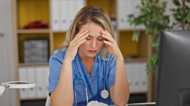 Young blonde woman doctor stressed working at clinic