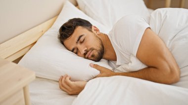 Genç İspanyol adam yatakta uzanıp yatak odasında uyuyor.