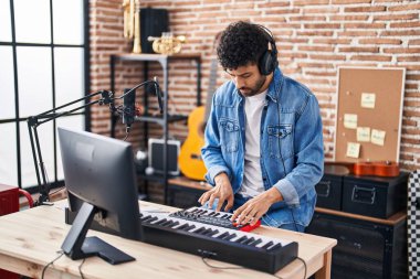 Genç Arap müzisyen müzik stüdyosunda piyano klavyesi çalıyor.