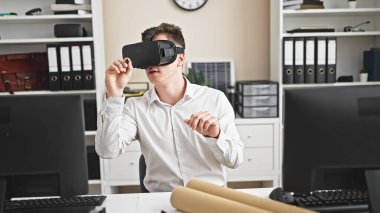 Sanal gerçeklik gözlüğü takan genç İspanyol mimar ofiste çizim yapıyor.