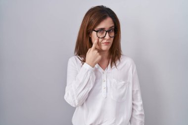 Esmer kadın, izole edilmiş beyaz arka planda dikiliyor. Gözü işaret ediyor. Senin hareketlerini izliyor. 