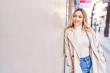 Young blonde woman smiling confident looking to the side at street
