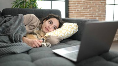 Evde kanepede uzanmış, köpekli İspanyol bir kadın film seyrediyor.