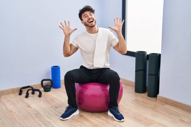 Sakallı İspanyol bir adam yoga odasında pilatese oturmuş kollarını kaldırmış ve gözleri kapalı heyecanla haykırarak başarının çılgınlığını kutluyor. Kazanan konsept 