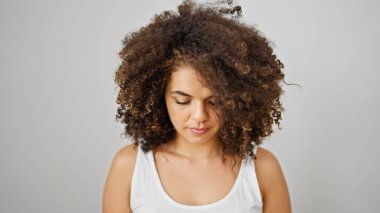 Genç ve güzel İspanyol kadın, izole edilmiş beyaz arka planda ciddi bir yüzle aşağıya bakıyor.