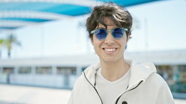 Young hispanic man smiling confident wearing sunglasses at park