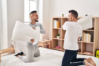 Two men couple fighting with pillows at bedroom