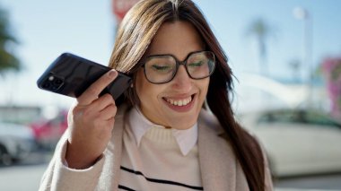 Genç ve güzel İspanyol kadın gülümsüyor. Caddedeki akıllı telefondan kendine güvenen bir sesli mesaj dinliyor.