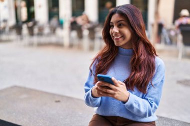 Sokakta akıllı telefon kullanan, kendine güvenen genç İspanyol kadın.