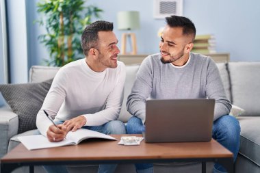 Evde dizüstü bilgisayarla yazan iki adam.