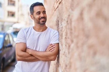 Genç İspanyol adam gülümsüyor. Kendine güveni tam. Sokakta çapraz hareketlerle duruyor.