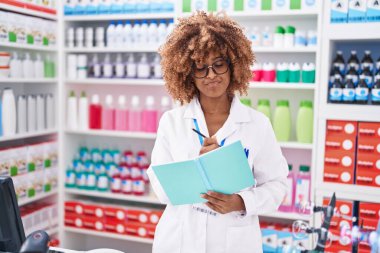 Afrika kökenli Amerikalı kadın eczacı eczanedeki belgeye yazı yazıyor.