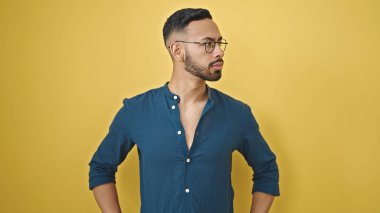 Genç İspanyol adam, yalıtılmış sarı arka plan üzerinden yan tarafa bakıyor.